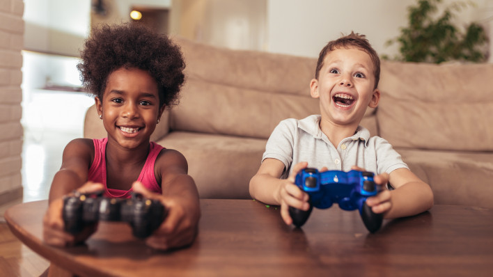 Boy and girl sitting in living room playing video game together