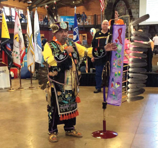 Robert Desjarlait at a powwow with a special eagle staff he created for cancer