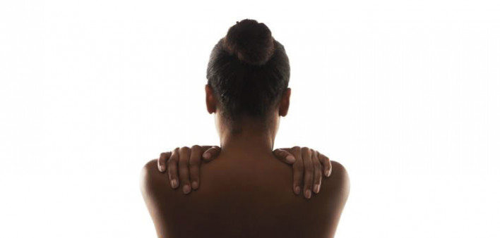 womans back with her hands on her shoulders