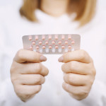 Woman hands opening birth control pills