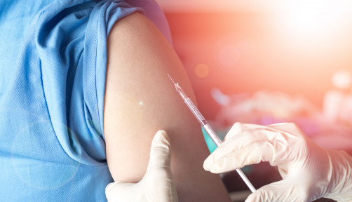 Vaccination healthcare concept. Hands of doctor or nurse in medical gloves injecting a shot of vaccine to a man patient.