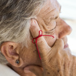 old woman with red string tied around index finger