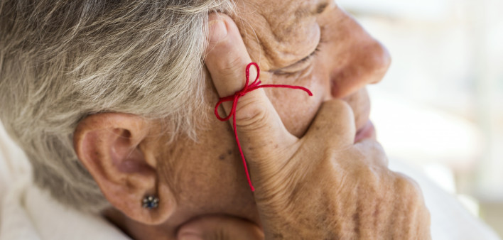 old woman with red string tied around index finger