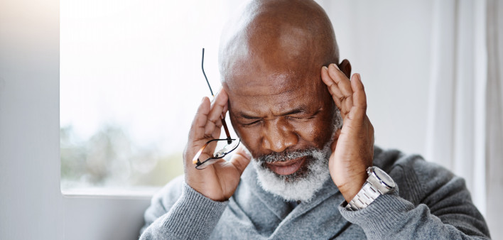 Shot of a handsome senior man suffering with a headache at home
