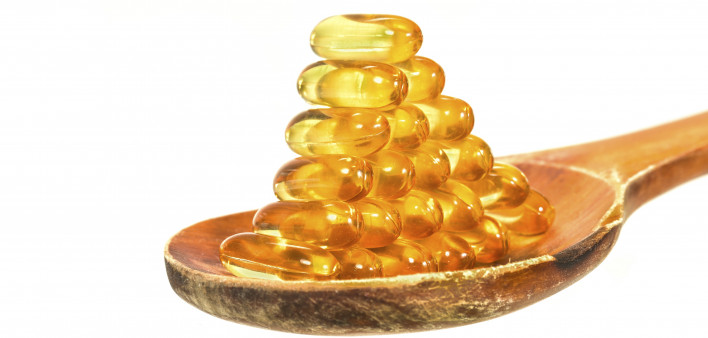 Vitamin D Capsules on wooden spoon