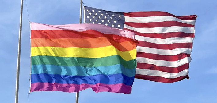 A Pride flag (with the original eight stripes) and the American flag fly over the Cherry Grove harbor on Fire Island, N.Y.