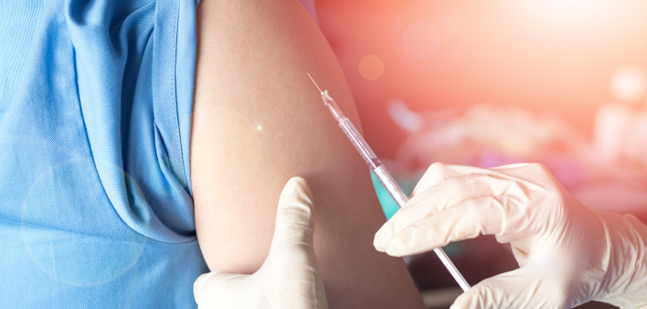 Vaccination healthcare concept. Hands of doctor or nurse in medical gloves injecting a shot of vaccine to a man patient.