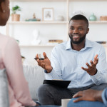 Family Psychotherapy. Friendly Black Therapist Consulting African American Couple At His Office