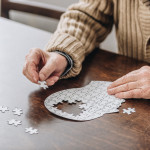 mans hands putting together puzzle pieces to make a head