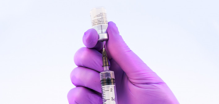 Doctor using Pfizer-BioNTech Covid-19 vaccine on a white background.
