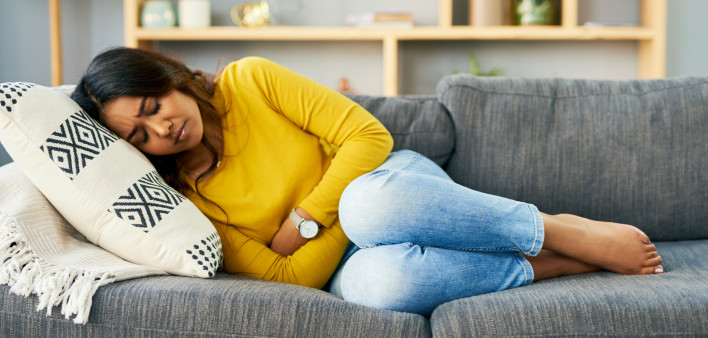 Shot of a young woman suffering from stomach cramps at home
