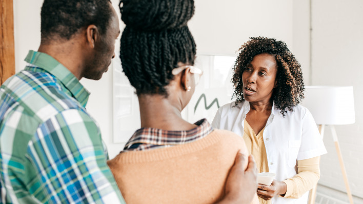 doctor having discussion with couple, the man has his arm around the woman