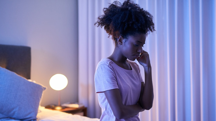 Cropped shot of a young woman sitting alone in her bedroom insomnia