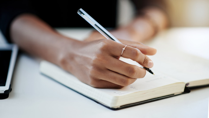 Closeup shot of a businesswoman writing in a notebook in an office