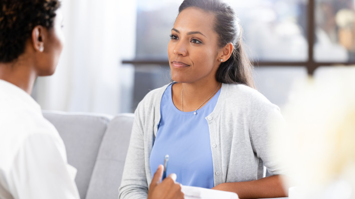 A mid adult female client is upset, uncomfortable, and possibly angry with the questions the unrecognizable female therapist asks.