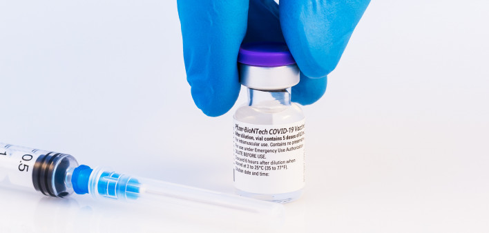 Doctor or scientist holding Pfizer-BioNTech Covid-19 vaccine on a white background.