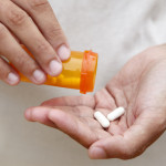Women pouring medicine into hand.