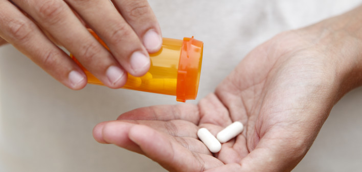 Women pouring medicine into hand.