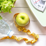 Green apple and Weight scale,measure tape with fresh vegetable, clean water and sport equipment for women diet slimming