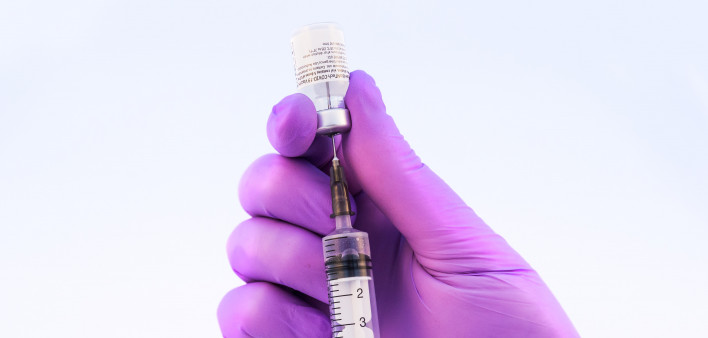 Doctor using Pfizer-BioNTech Covid-19 vaccine on a white background.