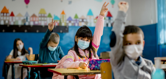 Elementary schoolchildren wearing a protective face masks in the classroom. Education during epidemic.