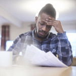 Worried young male reading through bank statements