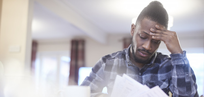 Worried young male reading through bank statements