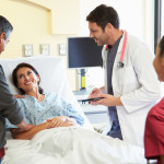 Happy Smiling Medical Team Meeting With Couple In Hospital Room