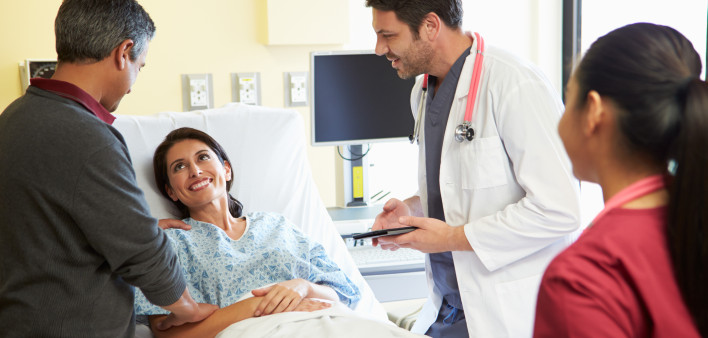Happy Smiling Medical Team Meeting With Couple In Hospital Room