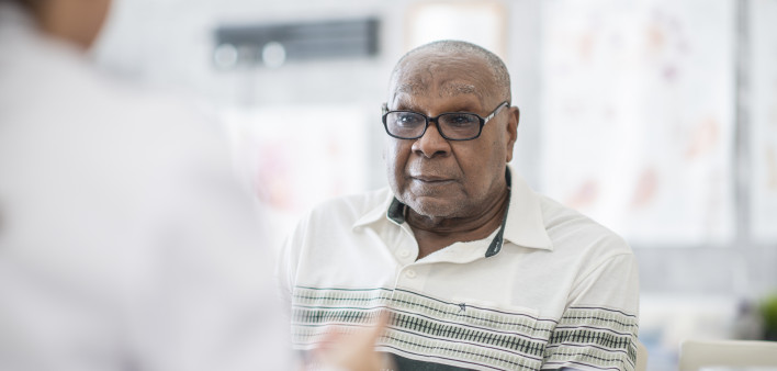 An African American man wearing eyeglasses sits in a doctor's office