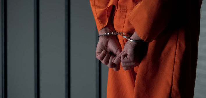 Prisoner with handcuffed arms behind back, another jail transfer, criminal