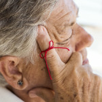 old woman with red string tied around index finger