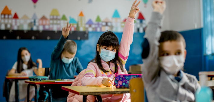Elementary schoolchildren wearing a protective face masks in the classroom. Education during epidemic.