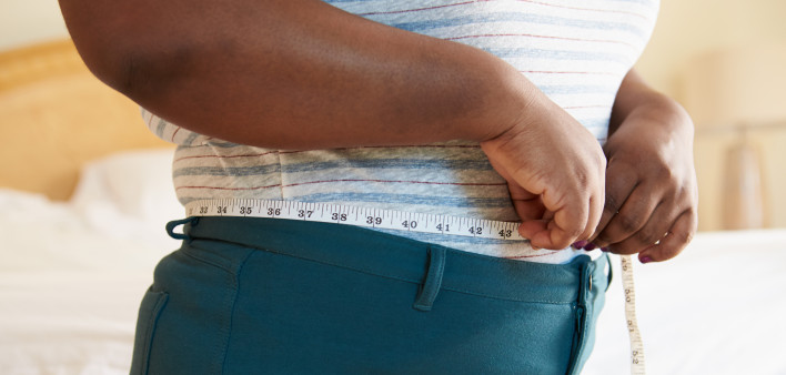 Close Up Of Overweight Woman Measuring Waist At Home Standing Still