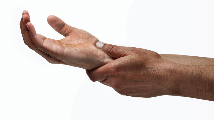 mans hands hold wrist pain