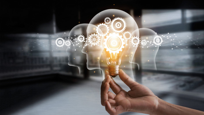 illustration of hand holding light bulb over head shapes and cogs