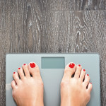 womans feet on scale red toe nails