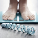 mans feet on scale with measuring tape on floor