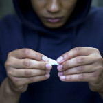 Teenager addict making cigarettes with marijuana, health problems risk, oncology