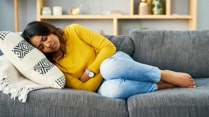 Shot of a young woman suffering from stomach cramps at home