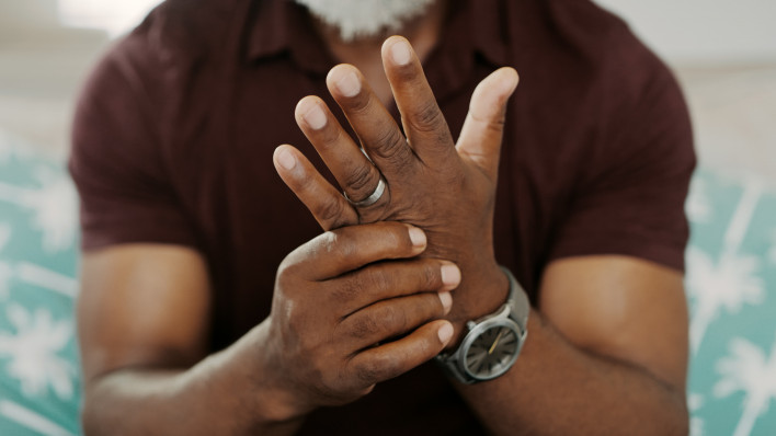 older black man holding hands in pain