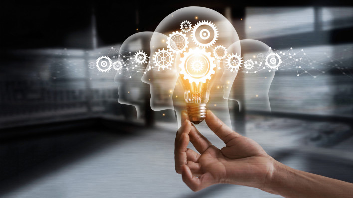 illustration of hand holding light bulb over head shapes and cogs