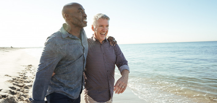older gay couple walking on the beach