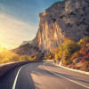 Asphalt road in autumn forest at sunrise. Crimean mountains