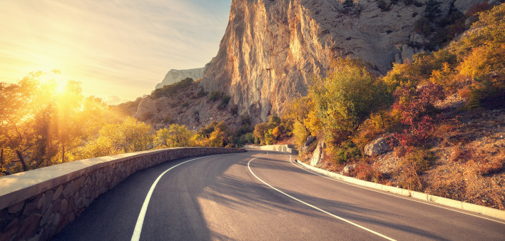 Asphalt road in autumn forest at sunrise. Crimean mountains