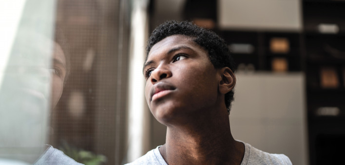 young black man looking at window