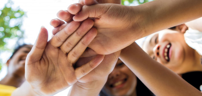 happy young people with hands joined in center