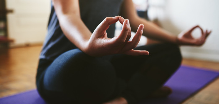 Cropped shot of an unrecognizable woman sitting on a yoga mat and meditating alone in her home