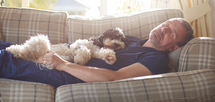 man sleeping on couch with his dog