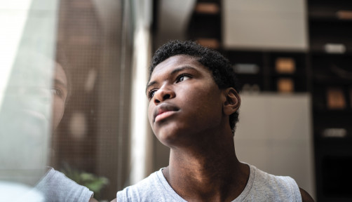 young black man looking at window